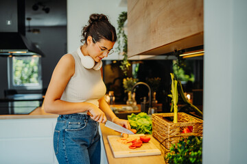 Young caucasian woman cutting vegetables in the kitchen

