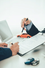 Salesperson at a table in a showroom Customer and new car, male car salesman stands beside and gives her advice Inside the shop where people sell cars Close-up pictures