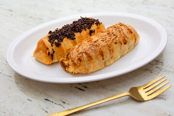 Two banana bolen cakes in chocolate and cheese flavors on a white plate