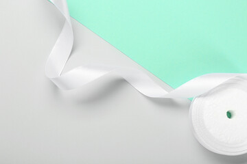 Beautiful white ribbon reel on color background, top view. Space for text