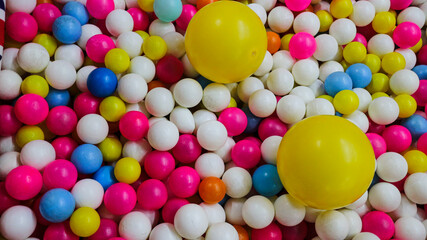 A vibrant and playful ball pit filled with colorful balls. The balls are various colors like yellow, pink, blue, white, and green, making a cheerful and fun environment for kids to play and have fun.
