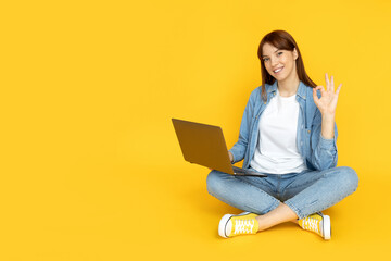 An attractive young girl is working on a laptop