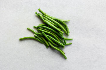 Overhead view of green beans being diced on a marble countertop, top view of green beans, dicing haricot verts on a white countertop