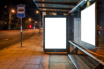 Vertical Mockup Of An Empty Bus Stop Advertising Light Box At Night. Blank Outdoor Billboard On City Street Sidewalk