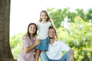 Fototapeta premium Happy family relaxing together at the park, caucasian family with father, mother, and children walking at the park.