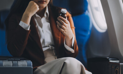 Photo of a frustrated woman sitting on an airplane with her head in her hands. Asian woman sitting...