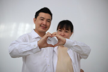 A young man hugs his pregnant wife while standing in a room in his house.