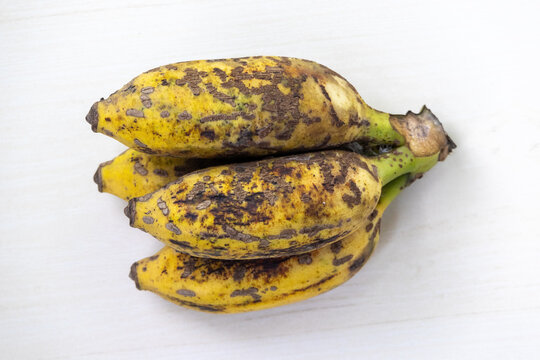 A bunch of ripe yellow bananas on a white background.