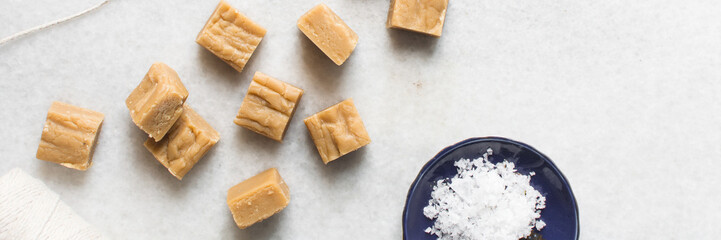 Overhead view of peanut butter fudge on a white marble tray, top view of soft peanut fudge squares on a white background