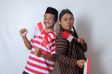 Portrait of two cheerful Asian man from Javanese and Madurese tribes celebrating independence day on 17 August while holding indonesian flag. Isolated image on white background