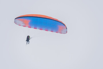 A colorful double paraglider flies in the sky
