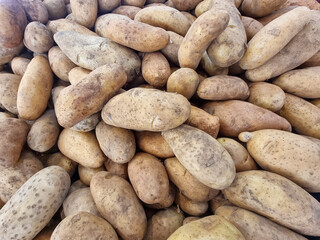 A lot of potatoes are placed in wooden crates in a vegetable market.