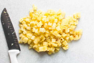 Top view of diced pineapples on a marble countertop, overhead view of chopped pineapples on a white...