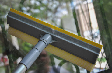 Close-up of window cleaner squeegee on blurred background. Selective focus