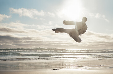 Beach, karate and man with training, kick and fitness with achievement, jump and practice. Active,...