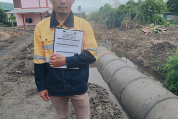 Asian male engineer works as a construction contractor in drainage systems, overseeing design,...