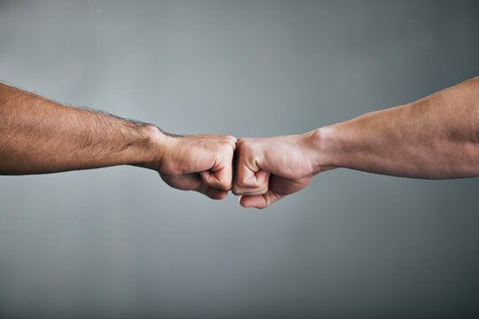 People, fitness and fist bump with greeting for teamwork, partnership or deal on a gray studio background. Closeup of men touching hands in agreement, unity or meeting for workout challenge together
