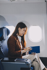 Young Asian executive excels in first class, multitasking with digital tablet, laptop and smartphone. Travel in style, work with grace.