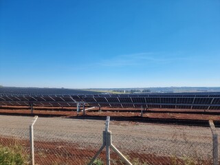 Fototapeta premium Solar panels in a vast array at a renewable energy farm under clear blue skies during the day
