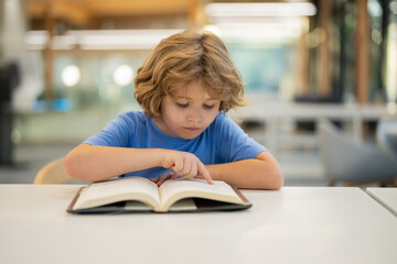Kid reading book. Child reading book in a public library. Cute little boy reading a book.