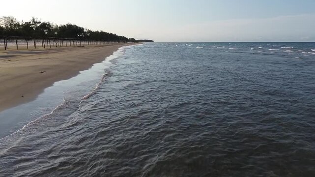 Flight of a drone taking off above the beach with a view of the horizon during sunset