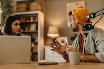 Couple enjoying a lively conversation while recording a podcast in their living room