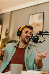 Man sitting comfortably in a living room, producing a podcast with headphones on