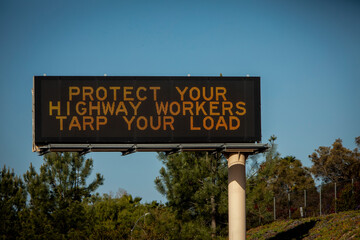 Obraz premium Digital freeway sign stating Protect Highway Worker Tarp Your Load