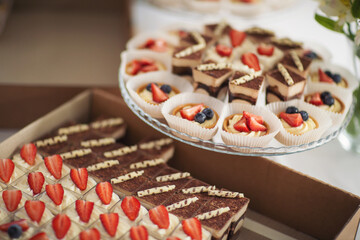 Holiday cupcakes in box, dessert decoration. toppings in a box, food preparation, catering concept. dessert food delivery in cardboard box for catering service.Tasty sweet desserts delivered for party