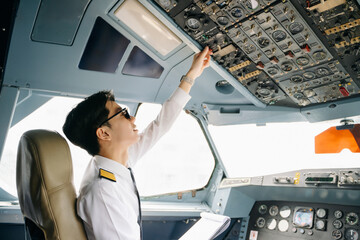 Asian Confident male pilot in uniform leaning at the passenger seat while standing inside of the airplane flight © Nuttapong punna