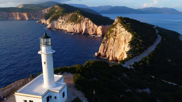 Drone shot of Lighthouse of Lefkas located in Cape Ducato surrounded by sea and mountains at sunset
