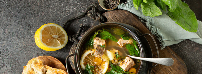 bowl of salmon and spinach soup on a dark table, top view