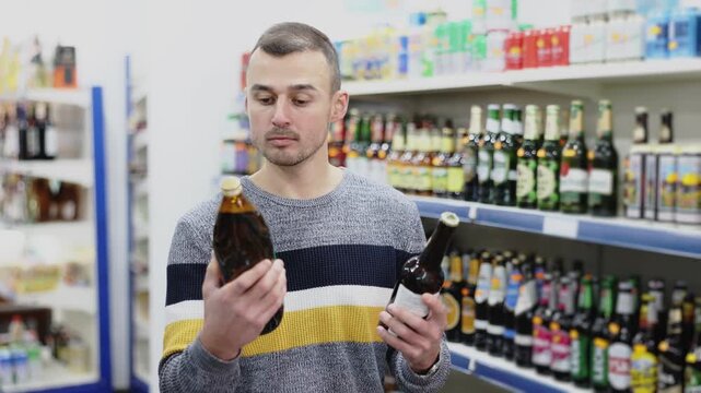 Adult male shopper in casual clothes chooses beer in grocery store