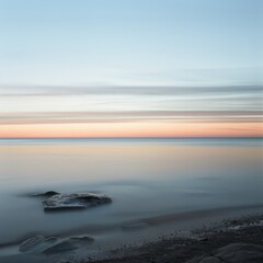 Serene seascape with a calm sea, a single rock, and soft pink and blue hues at sunset.