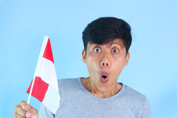 Excited young Asian men celebrate Indonesian independence day on 17 August by holding the...