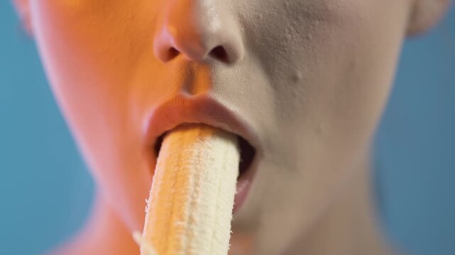 Unrecognizable woman eating a banana, close up mouth detail