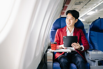 Young Asian executive excels in first class, multitasking with digital tablet, laptop and smartphone.