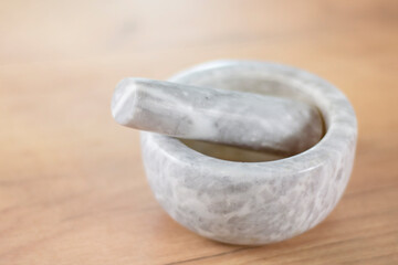 Light stone kitchen mortar and pestle on a wooden table.