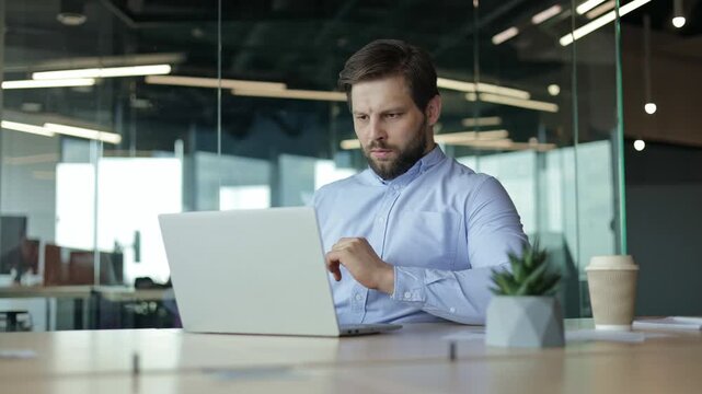Shocked businessman working at his desk in the office reacts to a loss on his laptop with disappointment and frustration.