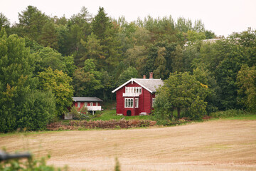 Small red wooden cabin house surrounded by nature in Norway