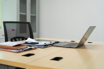 Naklejka premium An executive work desk sits in an office, meticulously arranged with documents and office supplies. The space is empty, awaiting the return of the executive to resume daily business activities.
