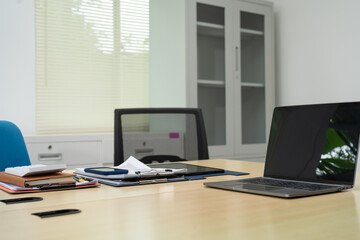 An executive work desk sits in an office, meticulously arranged with documents and office supplies. The space is empty, awaiting the return of the executive to resume daily business activities.