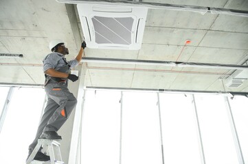 low angle view of african american handyman repairing air conditioner