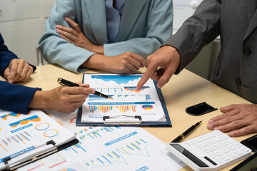 A businessperson  financial analyst during a corporate meeting. review a graph document, discussing financial data and strategies to ensure successful outcomes effective teamwork achieving corporate