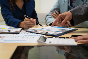 A businessperson  financial analyst during a corporate meeting. review a graph document, discussing financial data and strategies to ensure successful outcomes effective teamwork achieving corporate