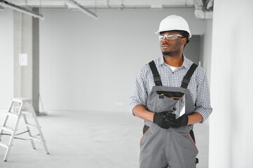 business, building, and people concept. african builder in hardhats with plastering tools indoors