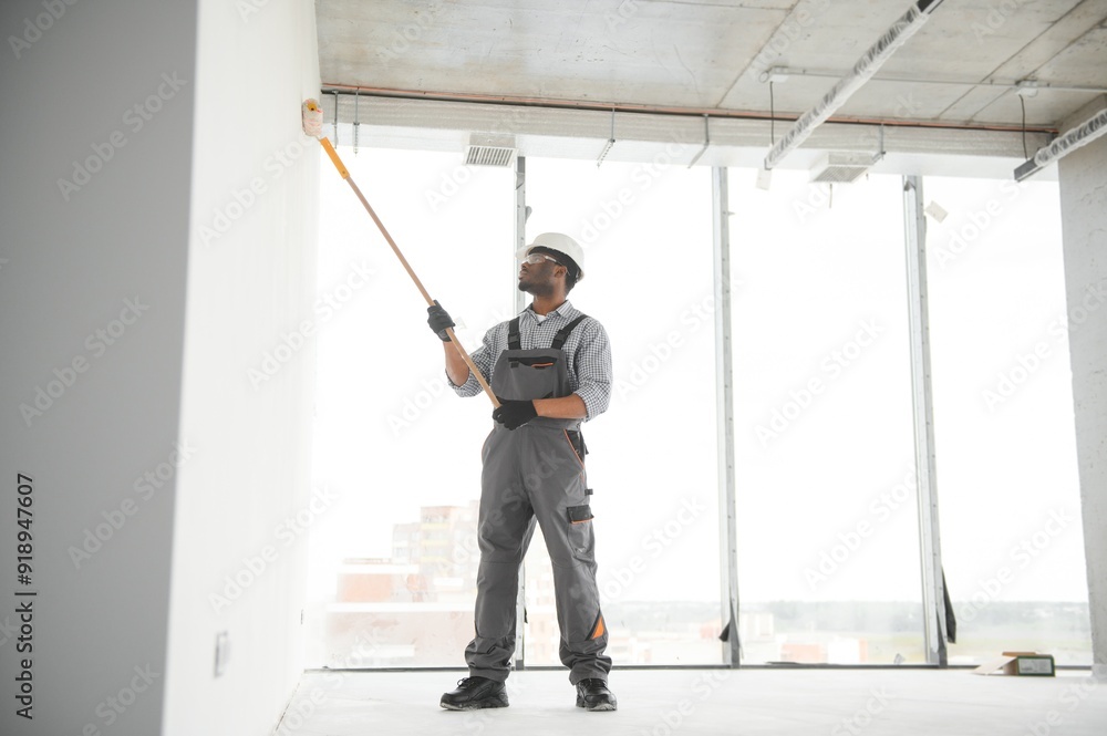 Wall mural African man paints a white wall with a roller. Repair of the interior