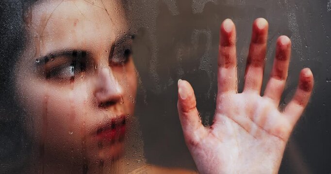 Woman touching steamy shower glass with hand