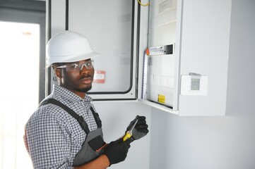 African american electrician Repairing electricity switchboard