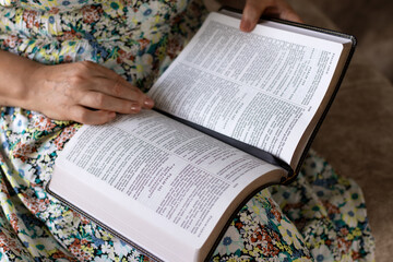 Senior Christian woman is reading and studying psalms in open holy bible book. Close-up. Selective...